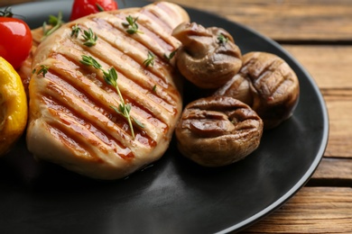 Tasty grilled chicken fillet with mushrooms on wooden table, closeup