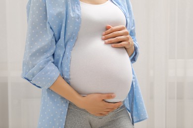 Photo of Pregnant woman in blue shirt indoors, closeup