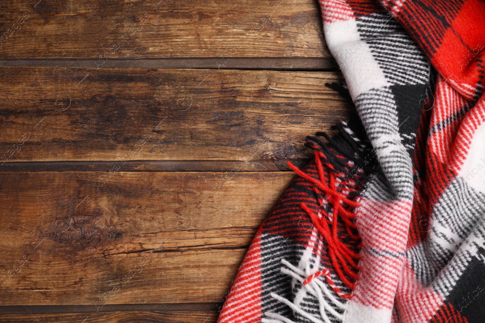 Photo of Checkered plaid on wooden table, top view. Space for text