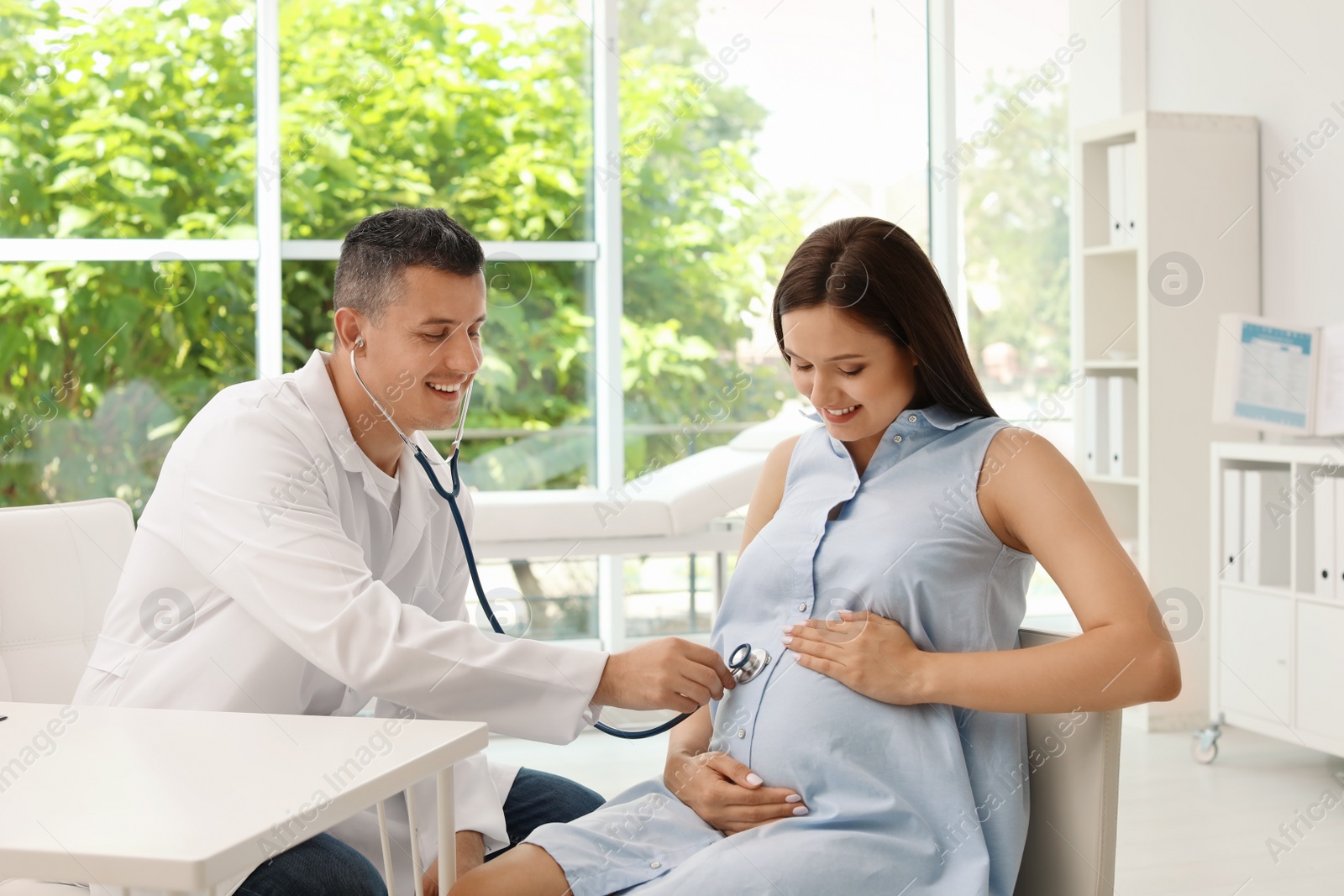 Photo of Young doctor examining pregnant woman in hospital. Patient consultation