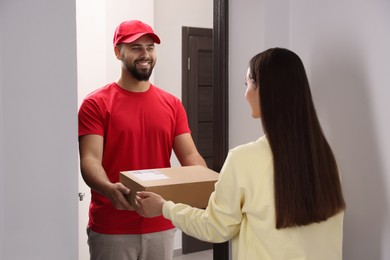 Photo of Woman receiving parcel from courier at home