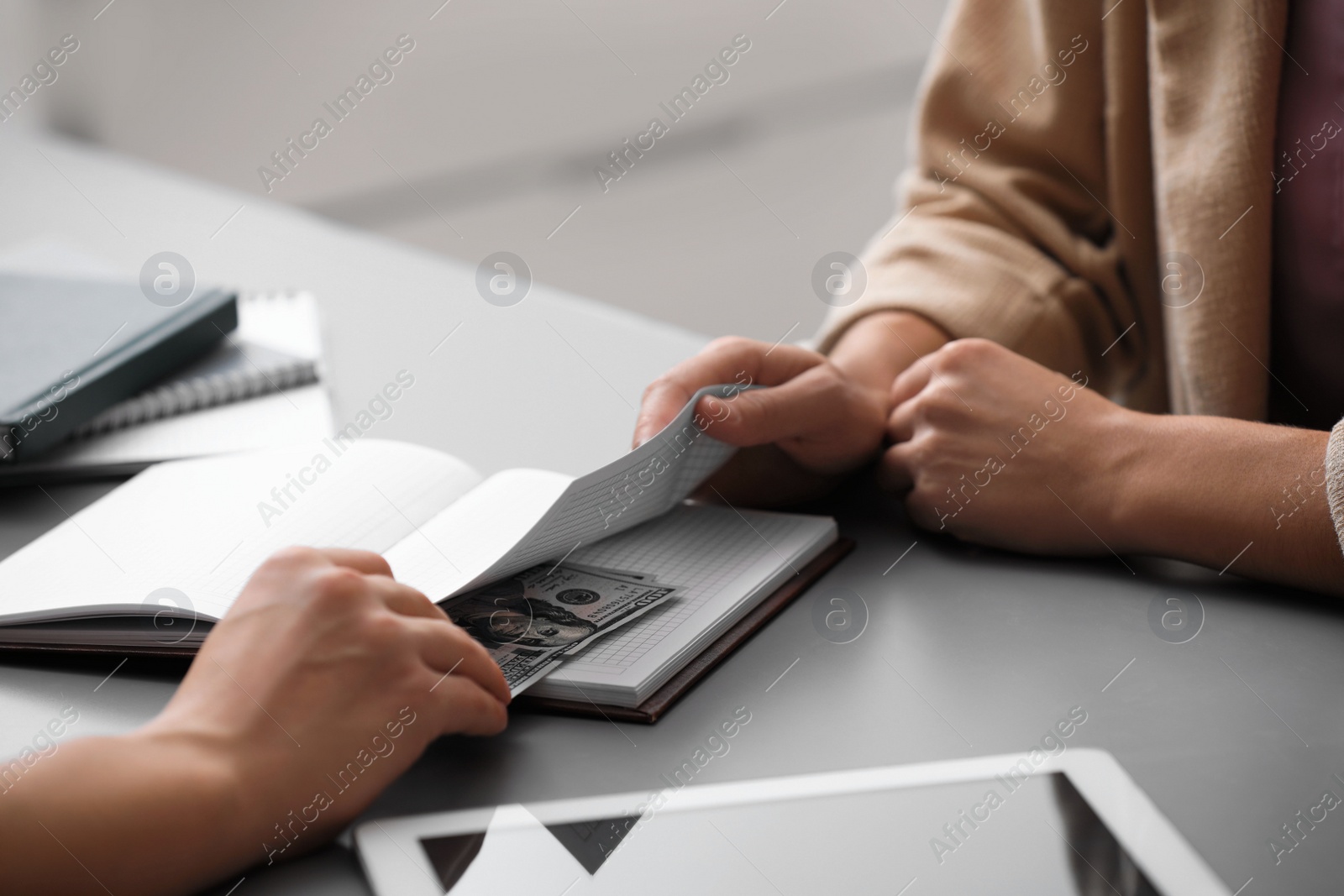 Photo of Man offering bribe money at table indoors, closeup