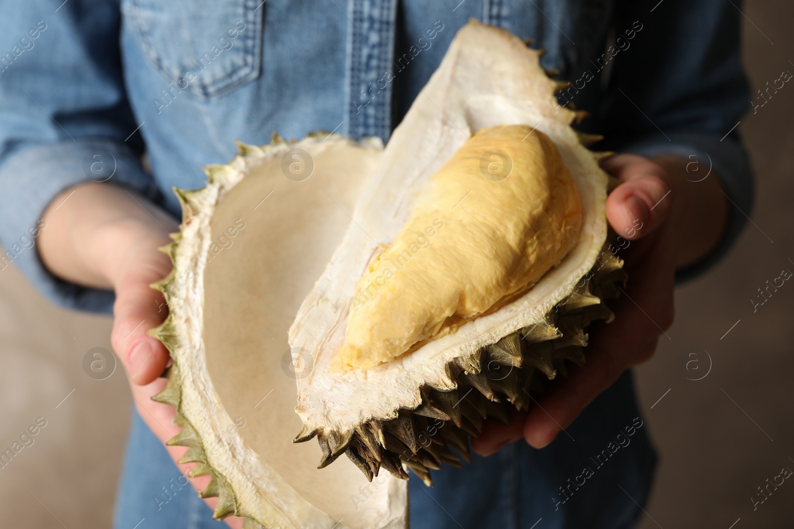 Photo of Woman holding ripe durian on grey background, closeup