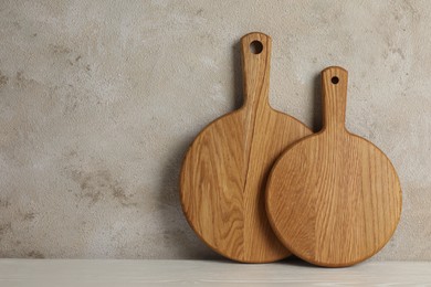 Photo of Wooden cutting boards on white table near textured wall, space for text