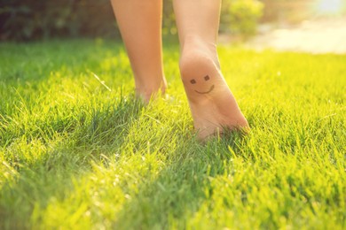 Teenage girl with smiling face drawn on heel walking outdoors, closeup