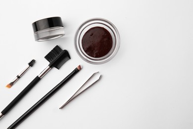 Flat lay composition with eyebrow henna and professional tools on white background, space for text