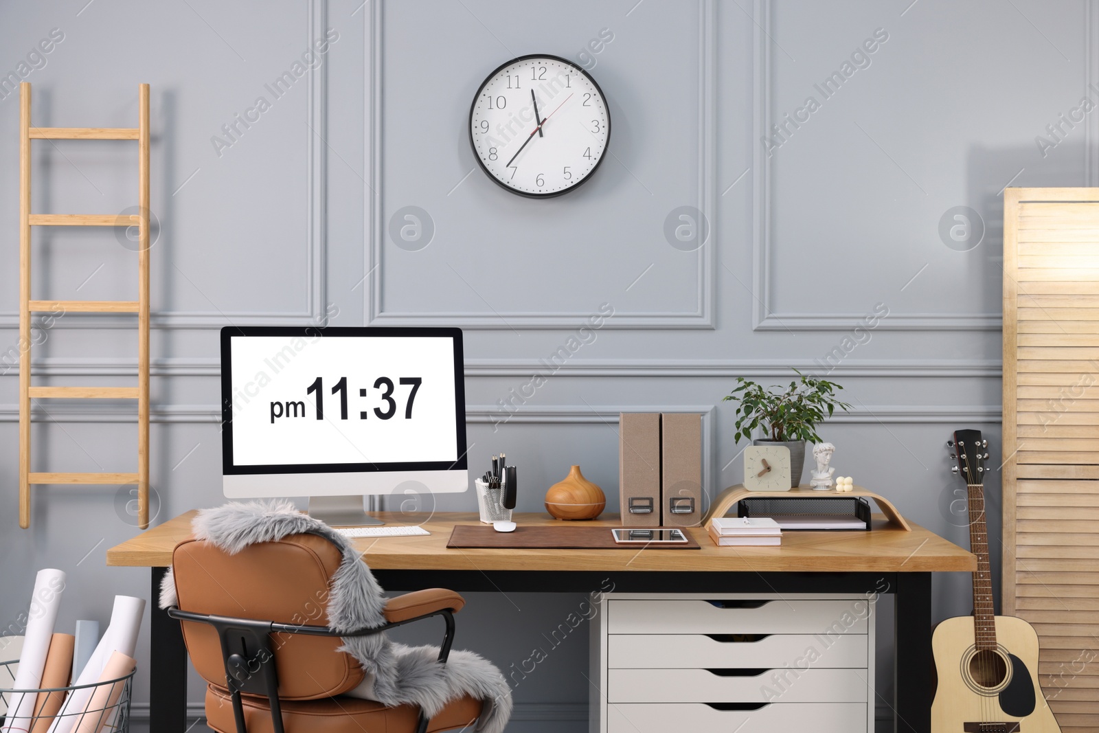 Photo of Stylish workplace with computer, houseplant and stationery on wooden desk near grey wall at home