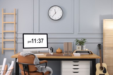 Photo of Stylish workplace with computer, houseplant and stationery on wooden desk near grey wall at home