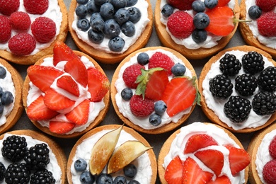 Photo of Many different berry tarts on table, top view. Delicious pastries