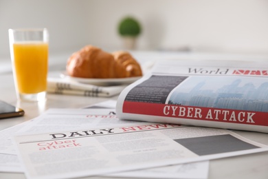 Photo of Newspapers with headlines CYBER ATTACK on table indoors
