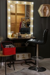 Photo of Makeup room. Stylish mirror near dressing table with beauty products and chair indoors