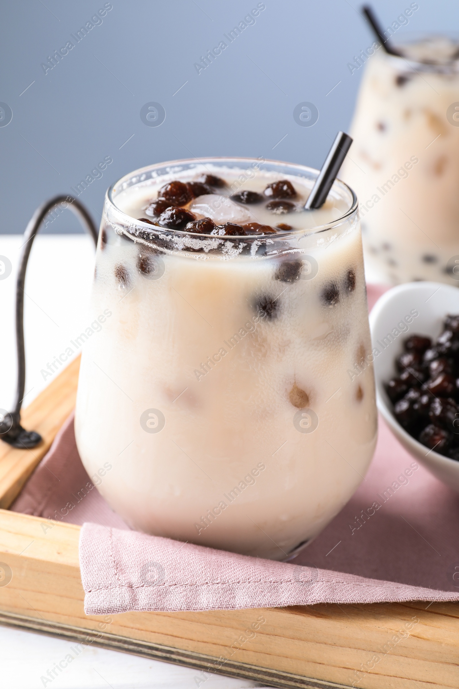 Photo of Bubble milk tea with tapioca balls on table against blue background