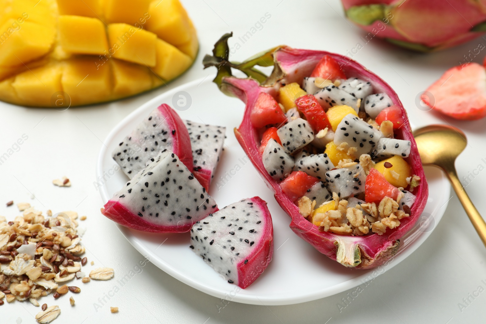 Photo of Yummy pitahaya boat with mango, granola and strawberry on white table