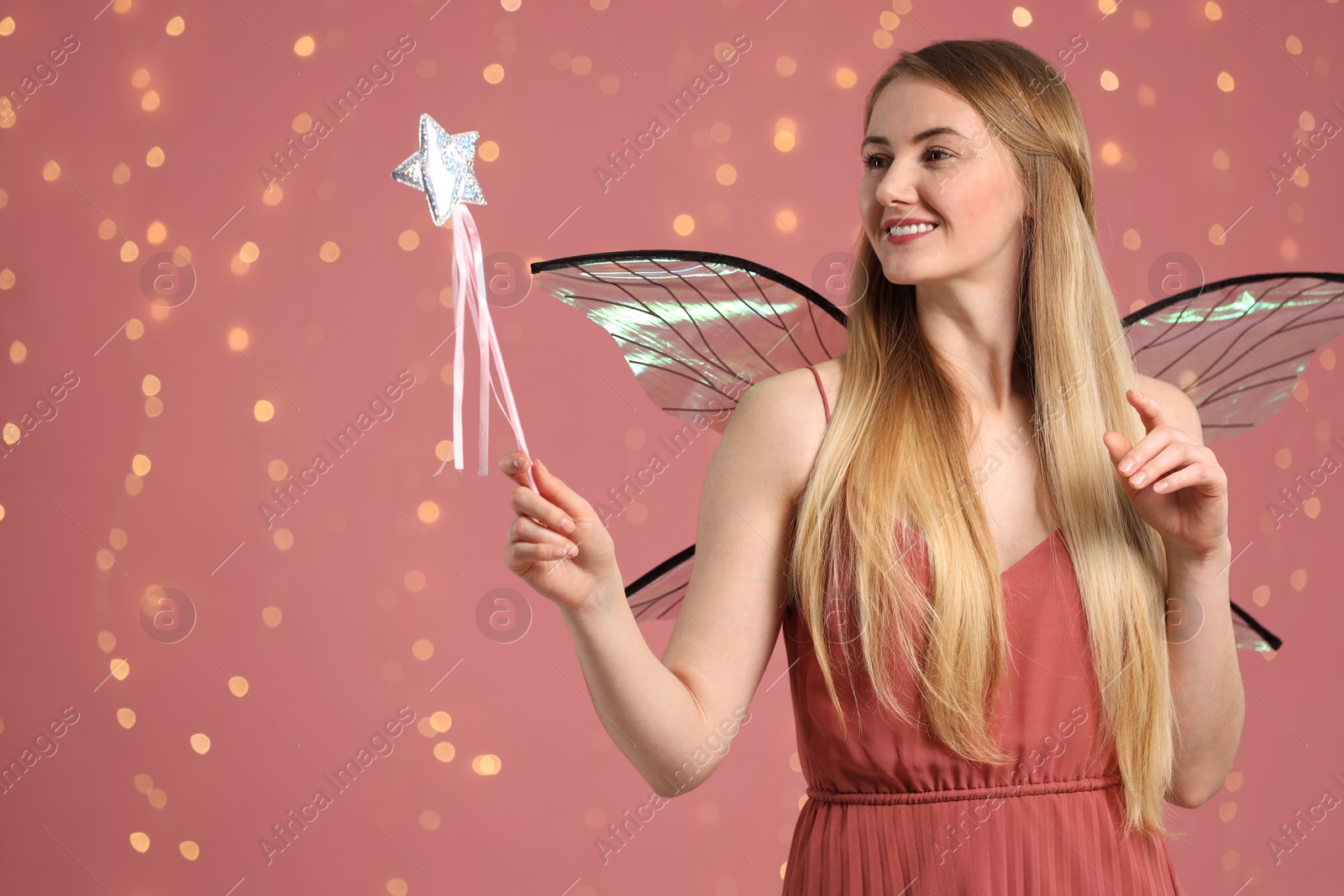 Photo of Beautiful girl in fairy costume with wings and magic wand on pink background, space for text