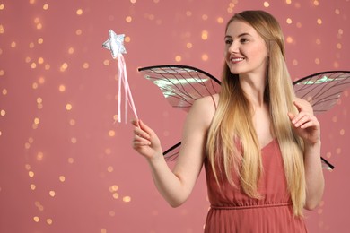 Photo of Beautiful girl in fairy costume with wings and magic wand on pink background, space for text