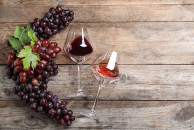 Photo of Flat lay composition with fresh ripe juicy grapes and wine on wooden table, space for text