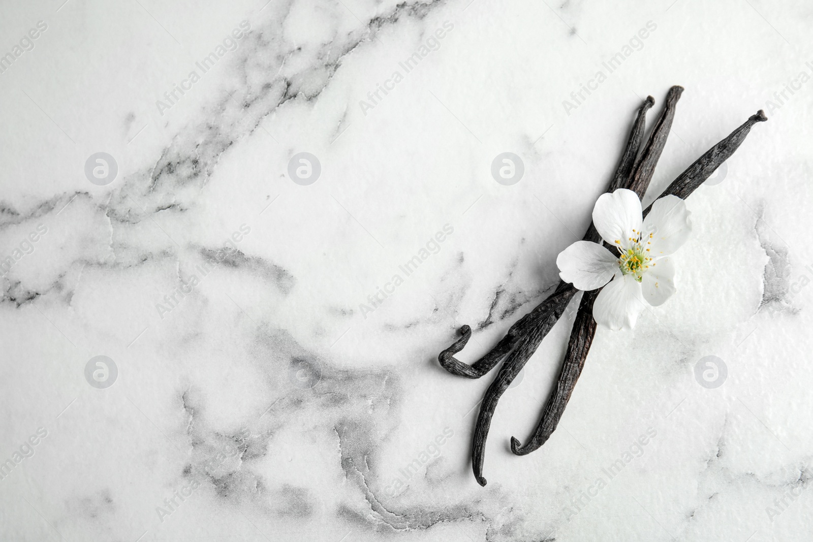 Photo of Flat lay composition with aromatic vanilla sticks and flower on marble background, space for text