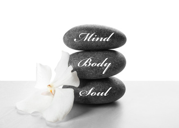 Photo of Stones with words MIND, BODY, SOUL and orchid flower on light background. Zen lifestyle