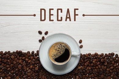 Cup of aromatic decaf coffee and beans on white wooden table, flat lay