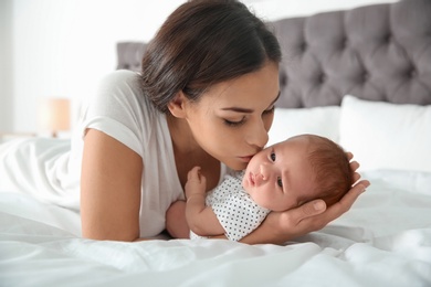 Photo of Young woman with her newborn baby on bed