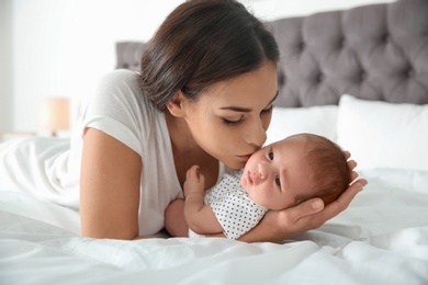 Young woman with her newborn baby on bed