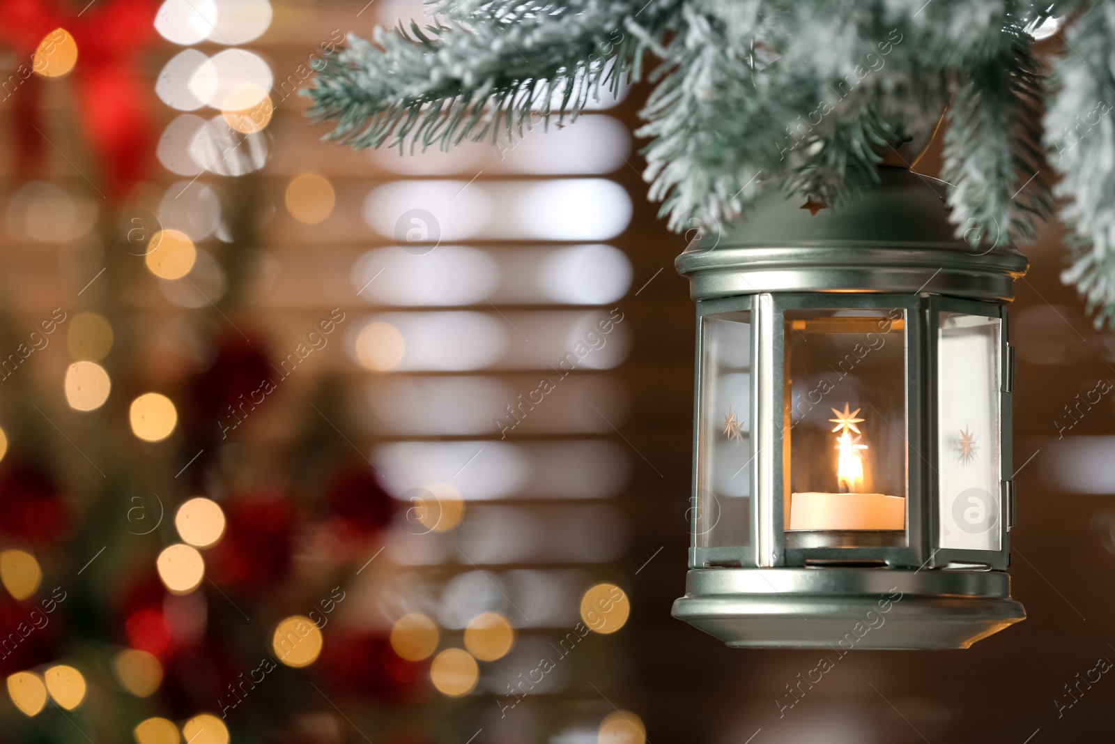 Photo of Beautiful Christmas lantern with burning candle hanging on fir tree branch in room. Space for text