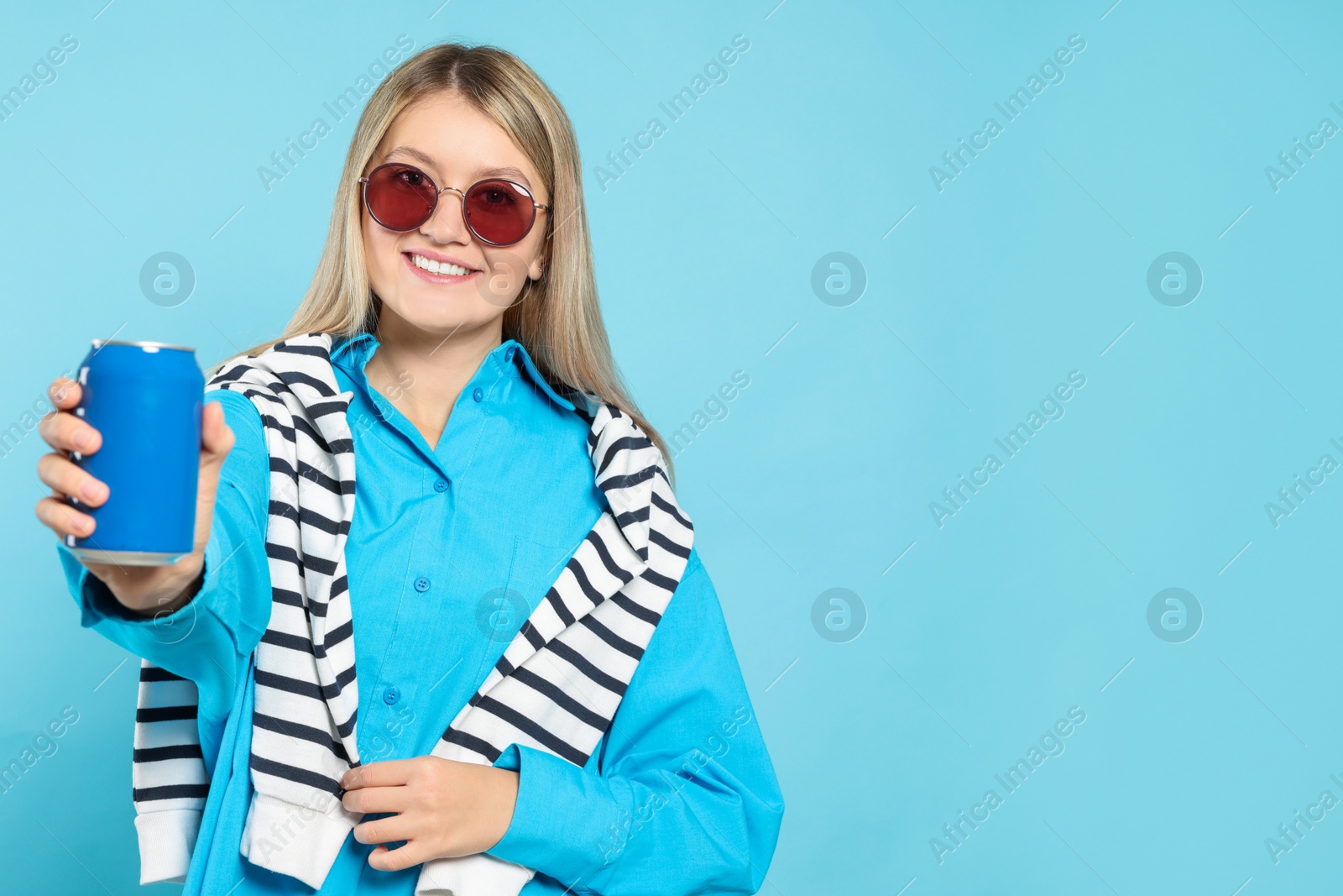 Photo of Beautiful happy woman holding beverage can on light blue background. Space for text