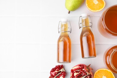 Photo of Tasty kombucha and fresh fruits on white tiled table, flat lay. Space for text