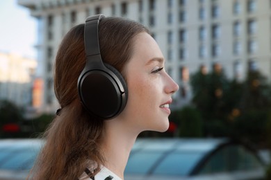 Beautiful woman in headphones listening to music on city street