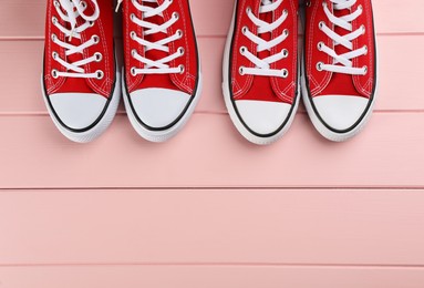 Photo of Red sneakers on pink wooden table, flat lay. Space for text