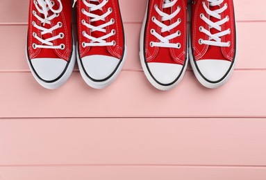 Red sneakers on pink wooden table, flat lay. Space for text