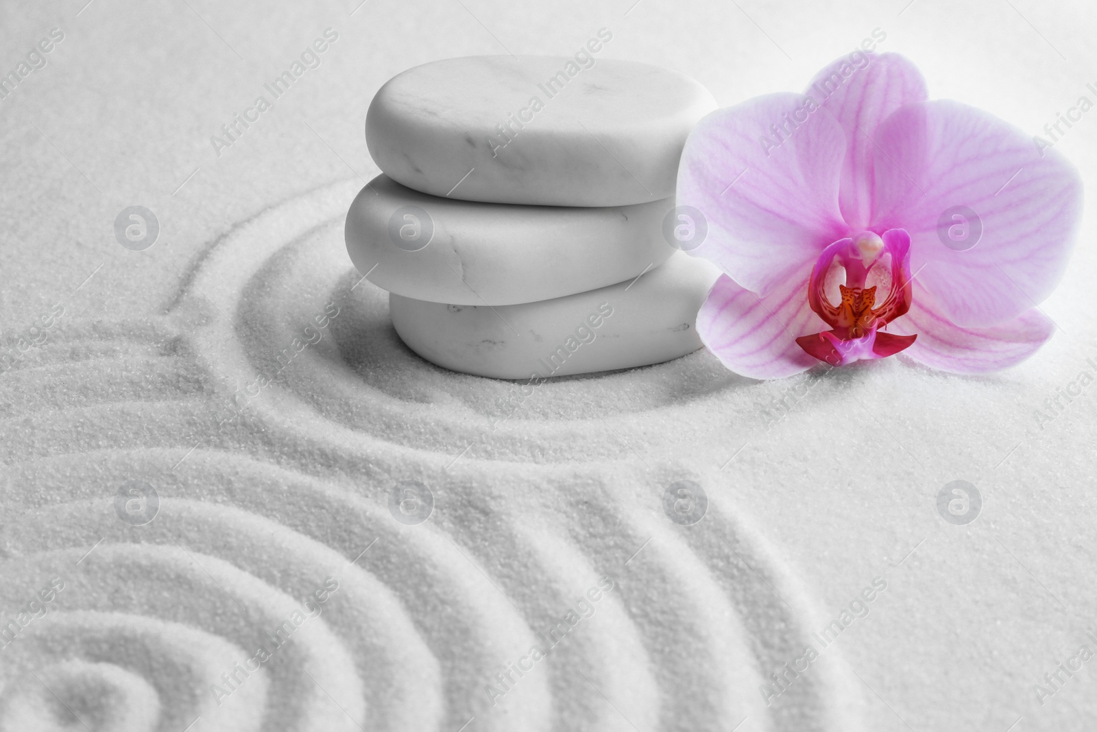 Photo of Stack of white stones and beautiful flower on sand with pattern. Zen, meditation, harmony