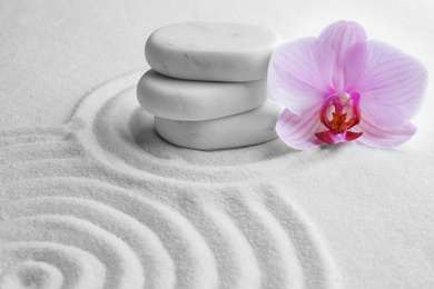 Photo of Stack of white stones and beautiful flower on sand with pattern. Zen, meditation, harmony