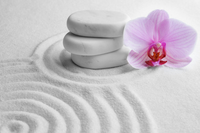 Stack of white stones and beautiful flower on sand with pattern. Zen, meditation, harmony