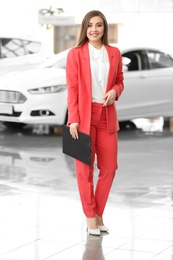 Young woman with clipboard in car salon