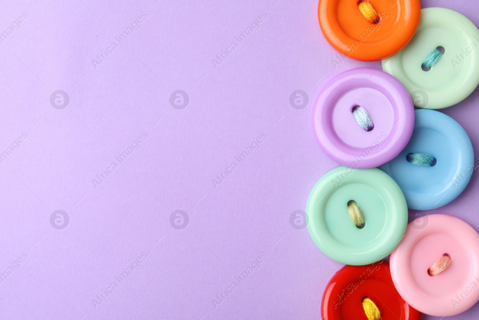 Photo of Many colorful sewing buttons on violet background, flat lay. Space for text