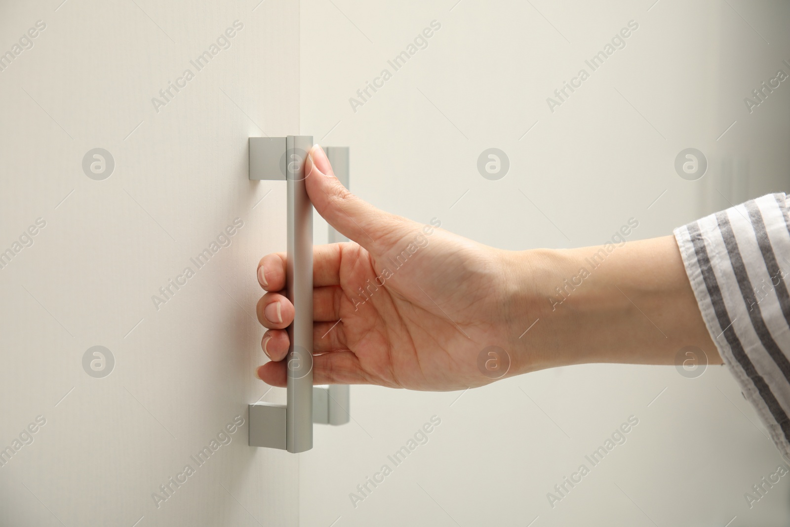 Photo of Woman opening cabinet door at home, closeup