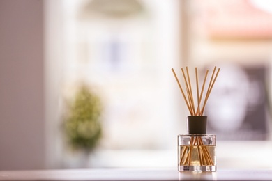 Photo of Aromatic reed air freshener on table against blurred background