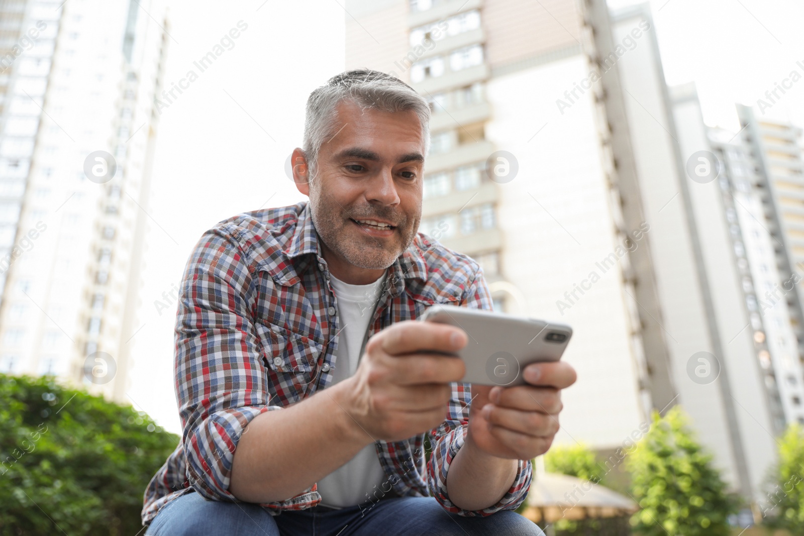 Photo of Portrait of handsome mature man using mobile phone in city center