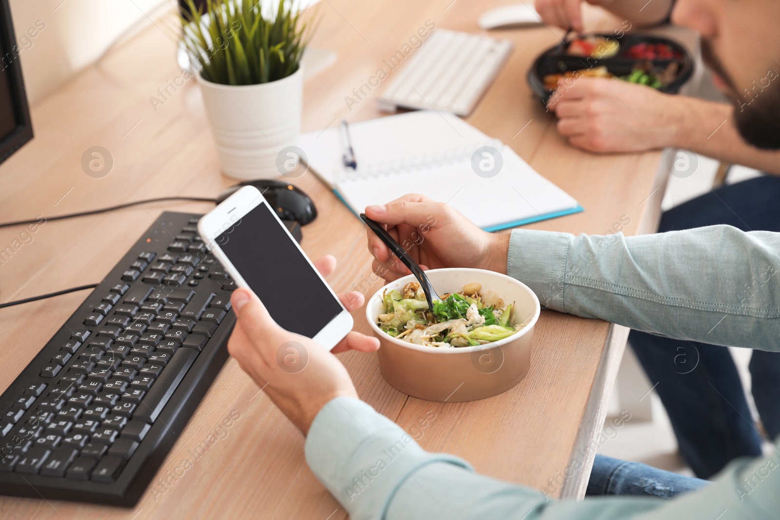 Photo of Office employee with smartphone having lunch at workplace, closeup. Food delivery