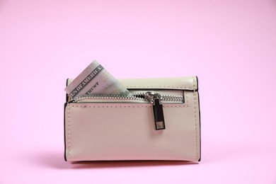 Photo of Stylish leather purse with dollar banknote on pink background