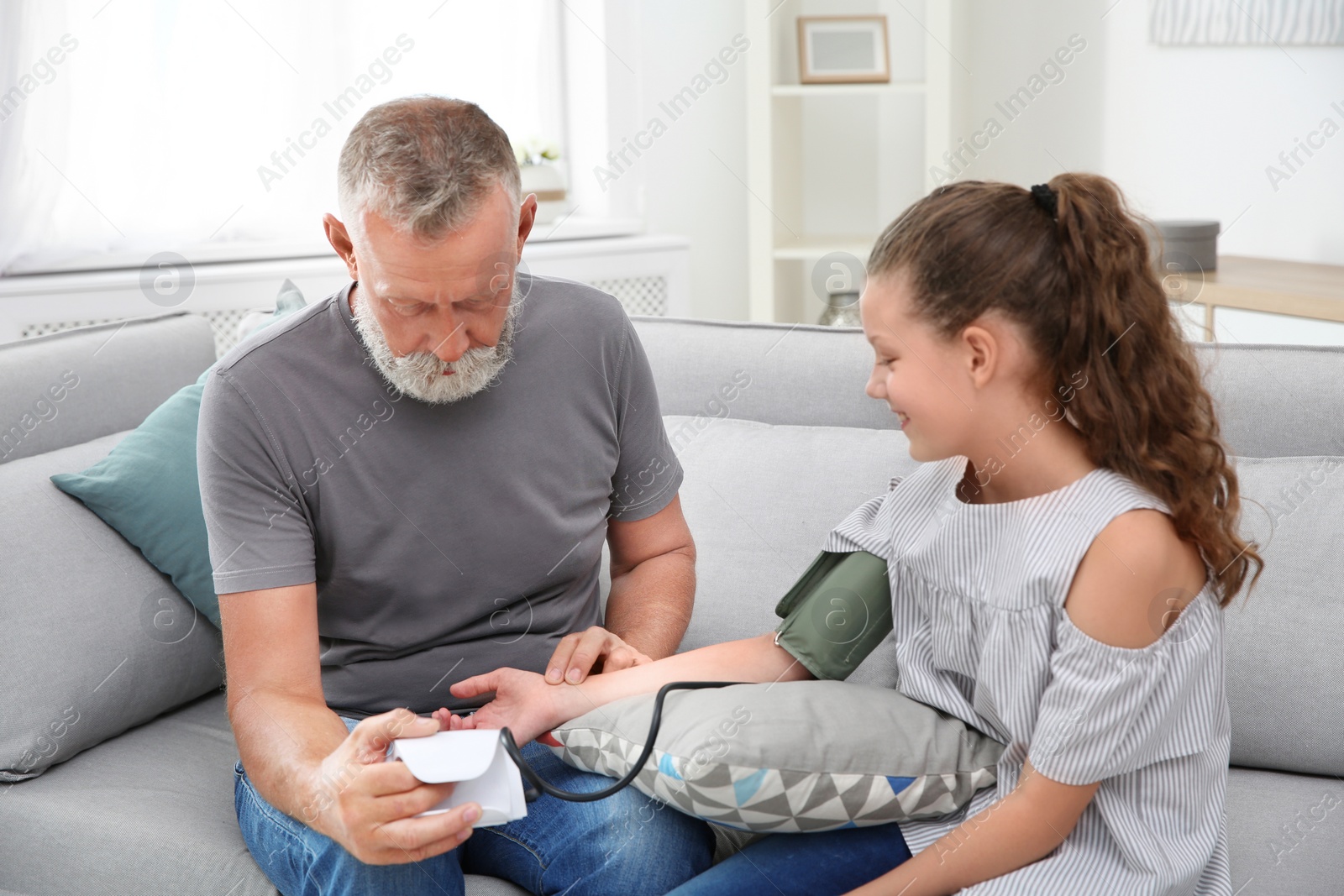 Photo of Senior man checking little girl's pulse indoors