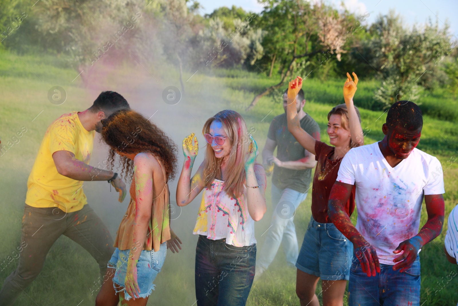 Photo of Happy friends having fun with colorful powder dyes outdoors. Holi festival celebration