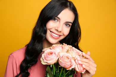 Photo of Portrait of smiling woman with beautiful bouquet on orange background