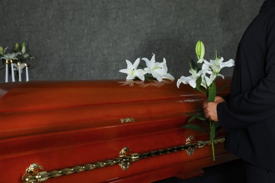 Young man near casket with white lilies in funeral home