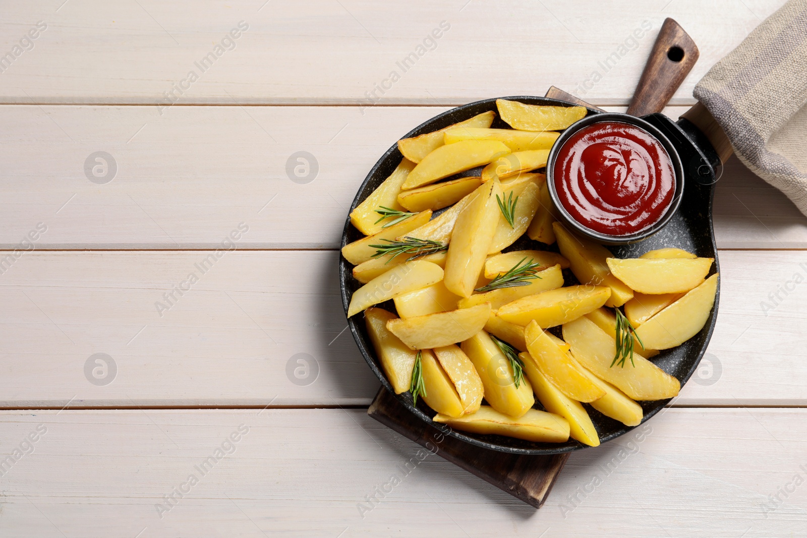 Photo of Pan with tasty baked potato wedges, rosemary and sauce on white wooden table, flat lay. Space for text