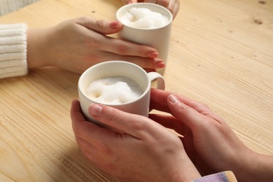 Photo of Women having coffee break at light wooden table, closeup