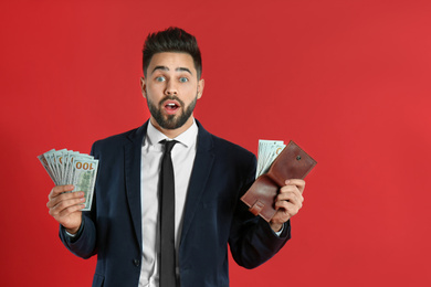 Emotional young man with money and wallet on crimson background