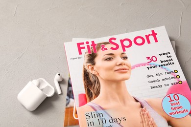 Sports magazines and wireless earphones on light grey table