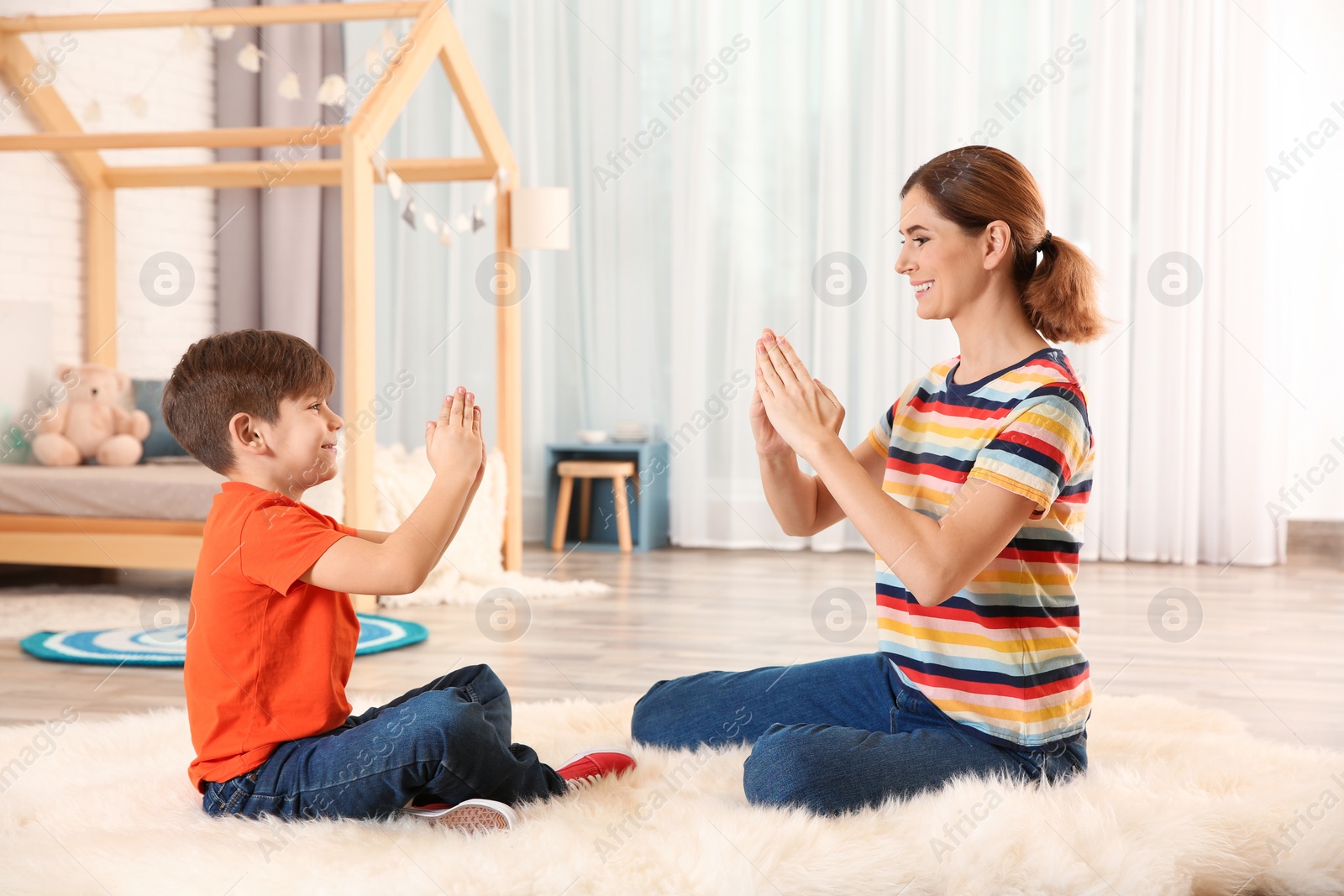 Photo of Hearing impaired mother and her child talking with help of sign language indoors